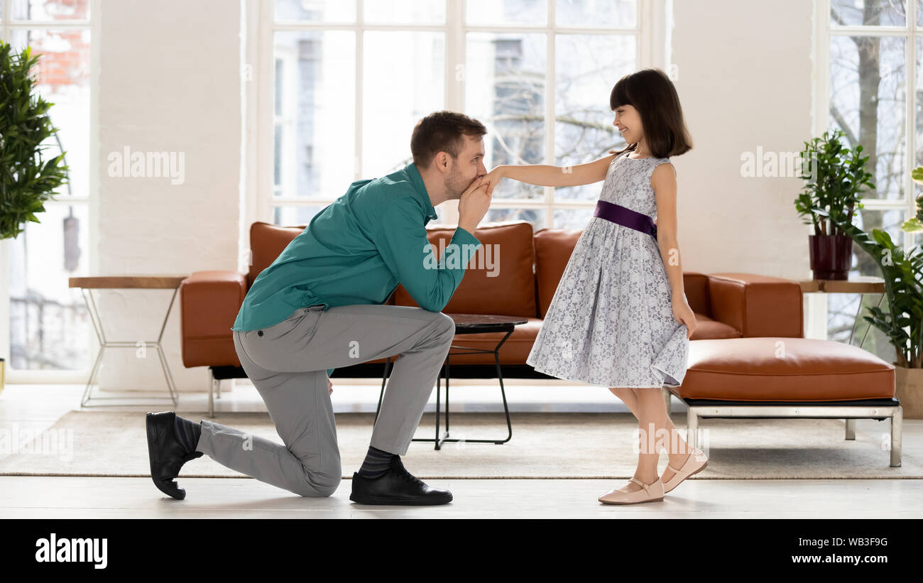 Dad standing on knee kissing hand of daughter after dance Stock Photo