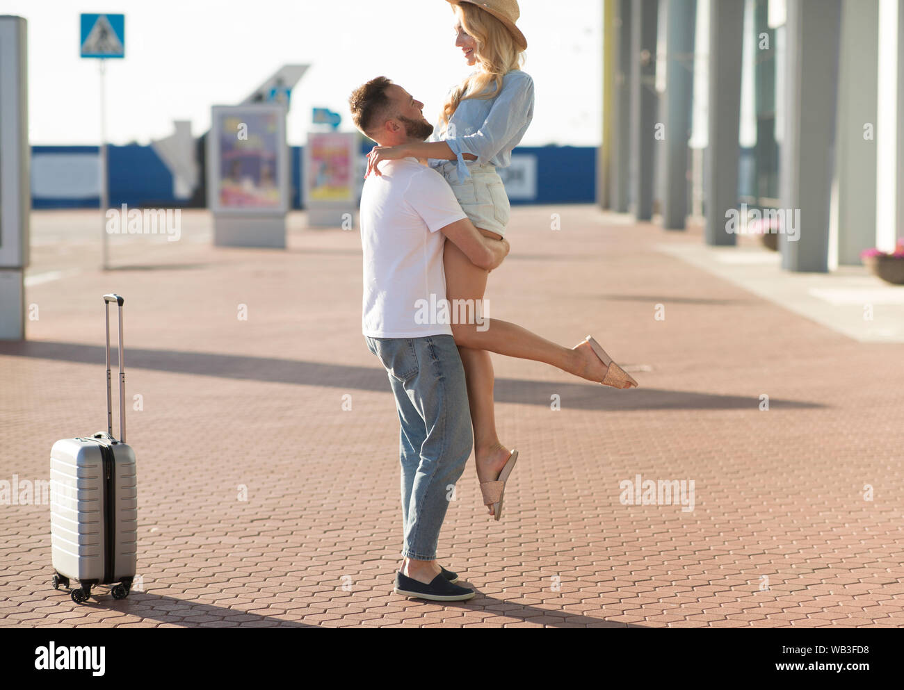 Couple meeting after long time, hugging near airport Stock Photo
