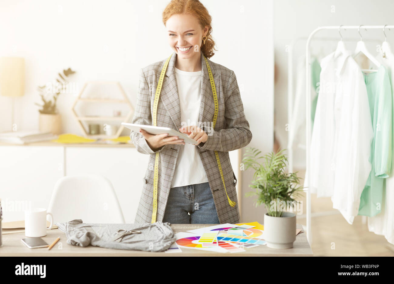 Excited dressmaker using digital tablet, working in atelier Stock Photo