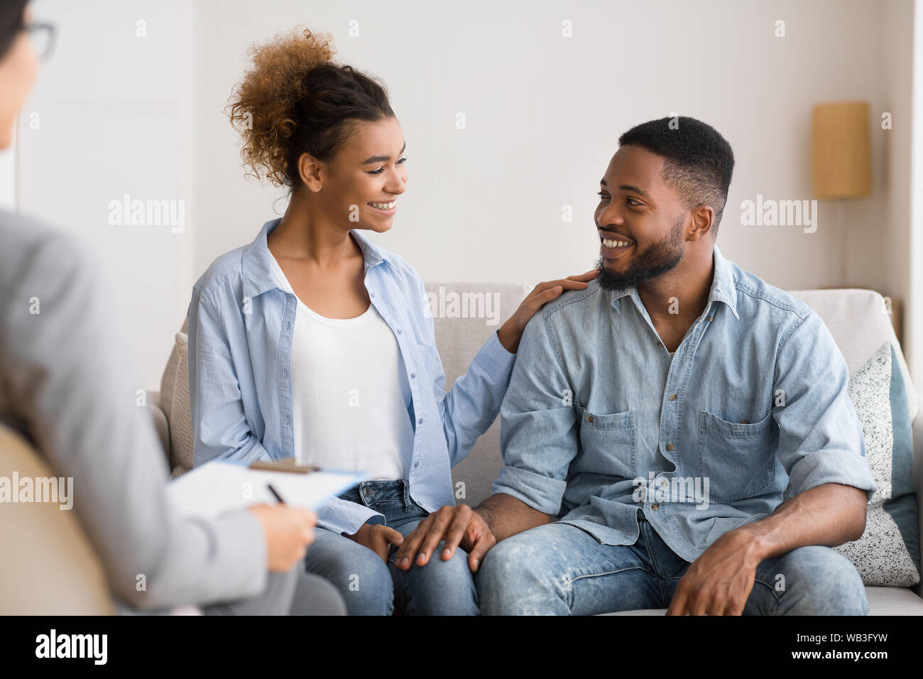 Afro Spouses Sitting At Marriage Counselor's Office After Happy Reconciling Stock Photo