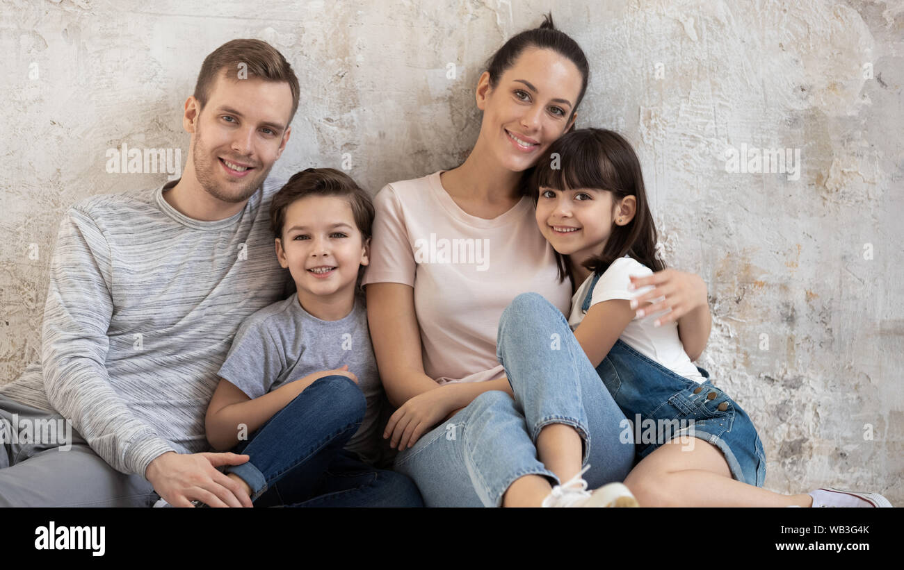Happy family sit on floor in apartment looking at camera Stock Photo