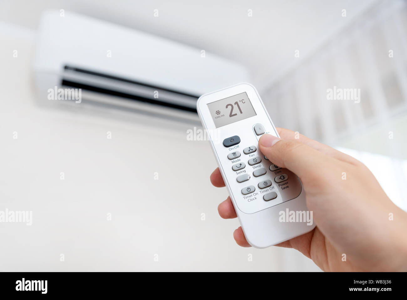 Hand with remote control directed on air conditioner. Home air conditioning concept Stock Photo