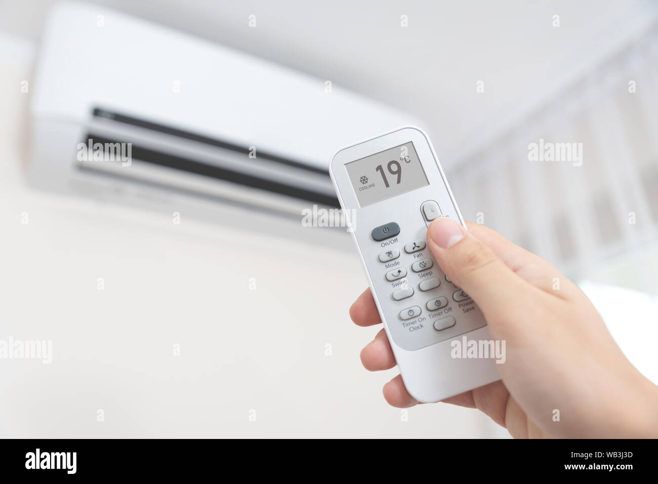 Hand with remote control directed on air conditioner. Home air conditioning concept Stock Photo
