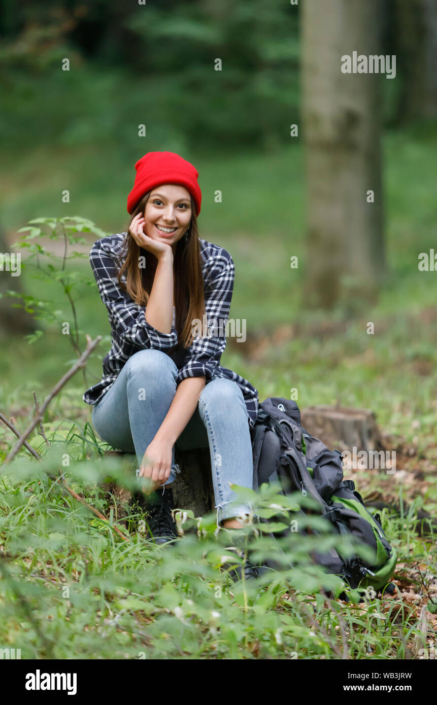 Calm beautiful smiling young woman wearing red hat enjoying fresh air outdoor, relaxing at the forest Stock Photo