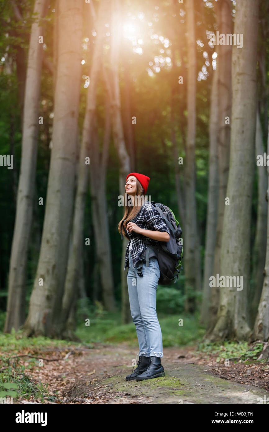 Skinny young woman is hiking by the wooden path in the middle of lush pine forest Stock Photo