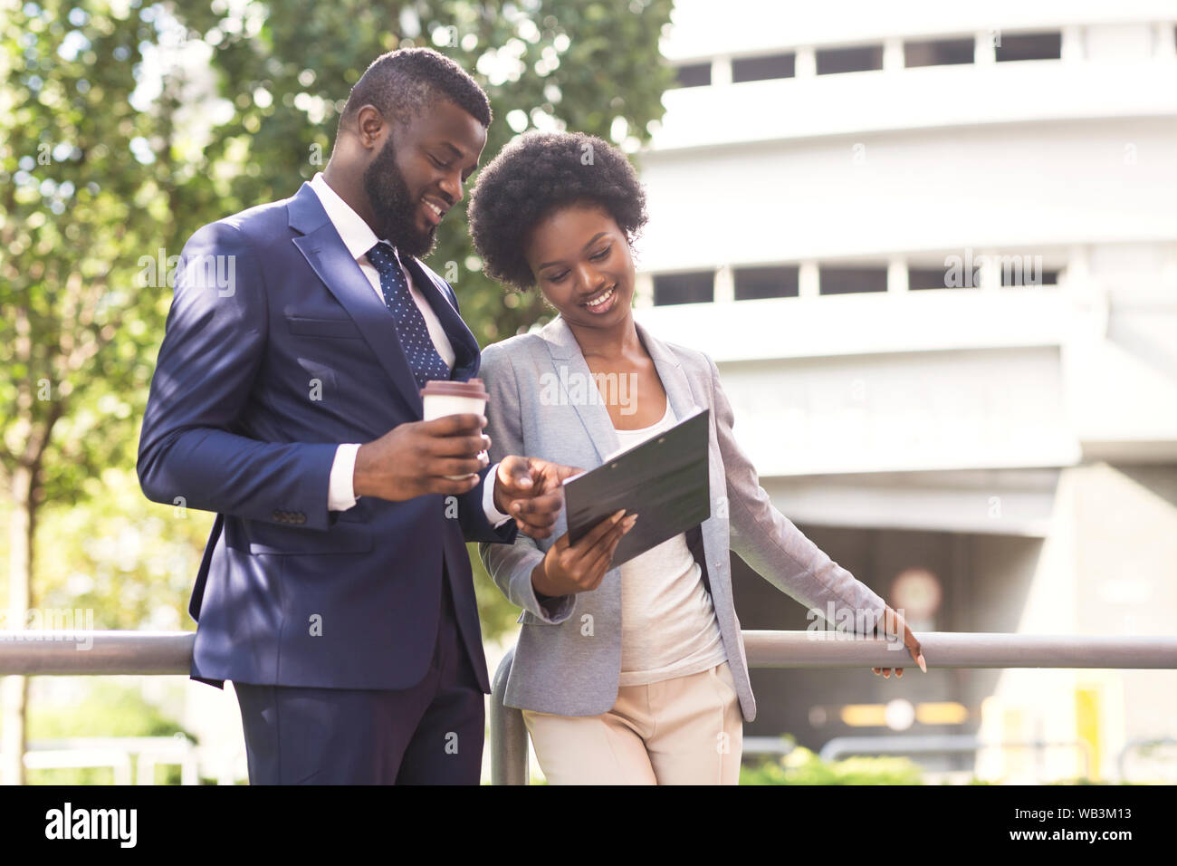 Two smiling coworkers discussing new project while standing outdoors Stock Photo
