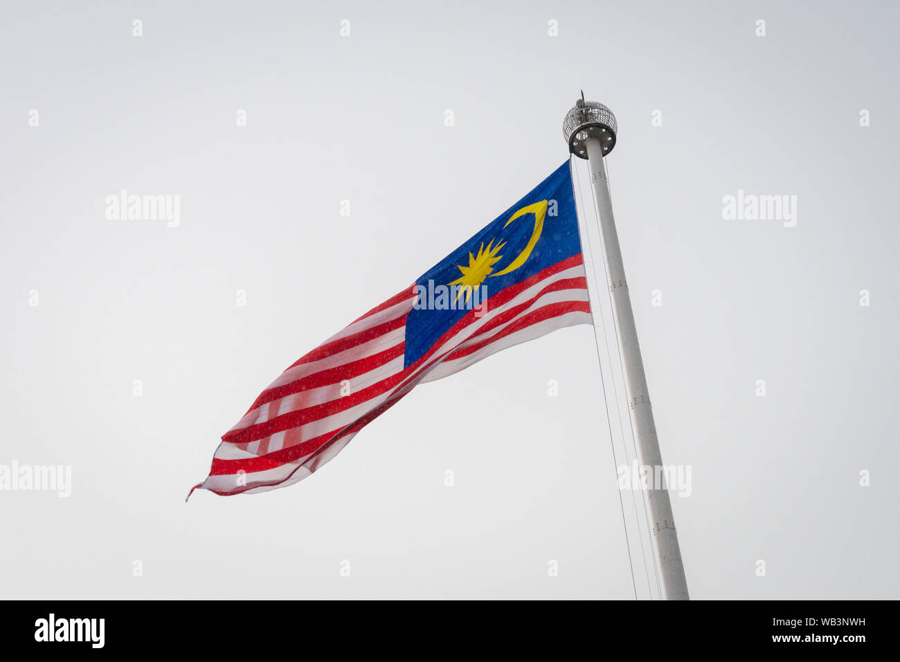 Malaysian national flag on huge flag pole during heavy rain Stock 