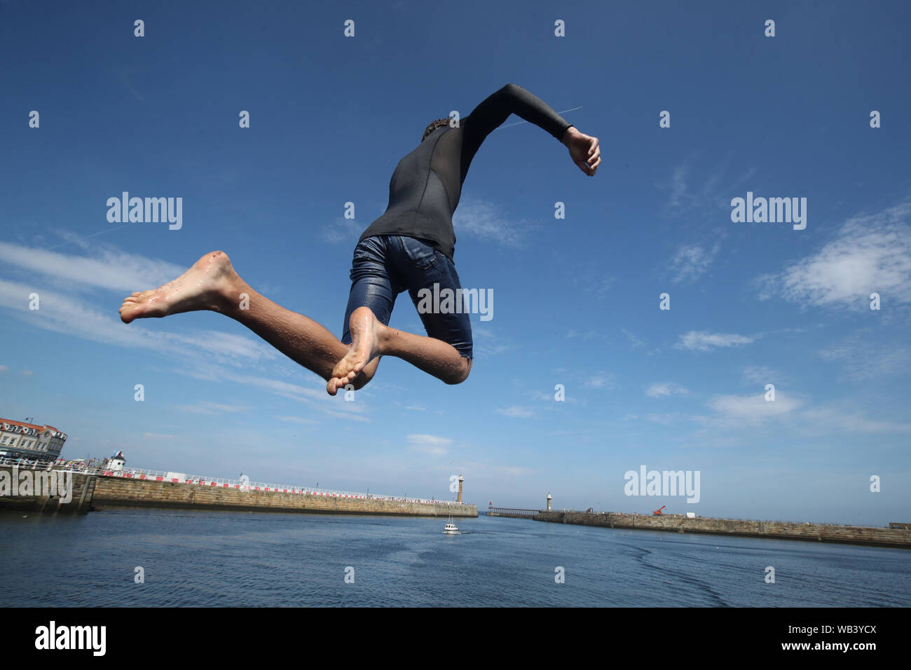 People jumping into the sea at Whitby Abbey in Yorkshire, as a bank holiday heatwave will see most of the country sizzling in sunshine with possible record temperatures, the Met Office has said. Stock Photo