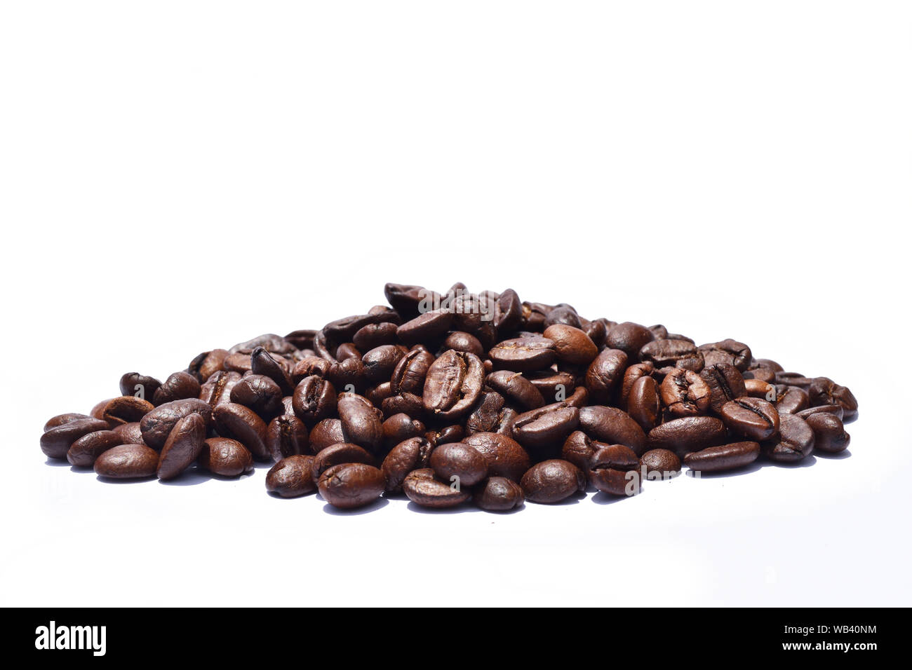 Pile of Dark brown roasted coffee beans isolated on white background, Raw processed food for drinks refreshment Stock Photo
