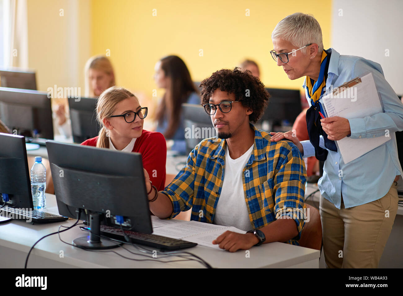 Woman lecturer in computer class assisting student on campus Stock Photo