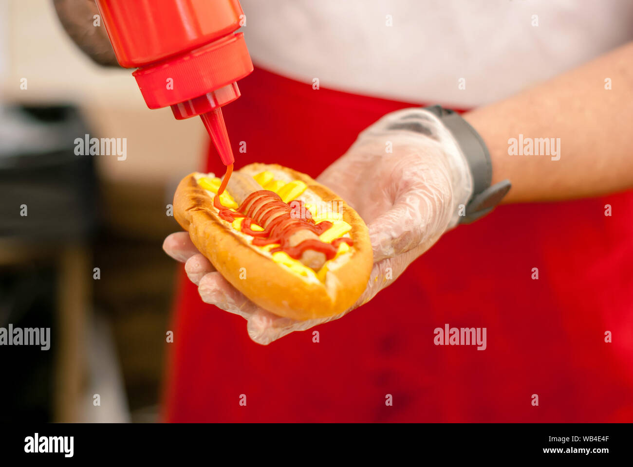 hands of street chef adding ketchup on hot dog close up Stock Photo