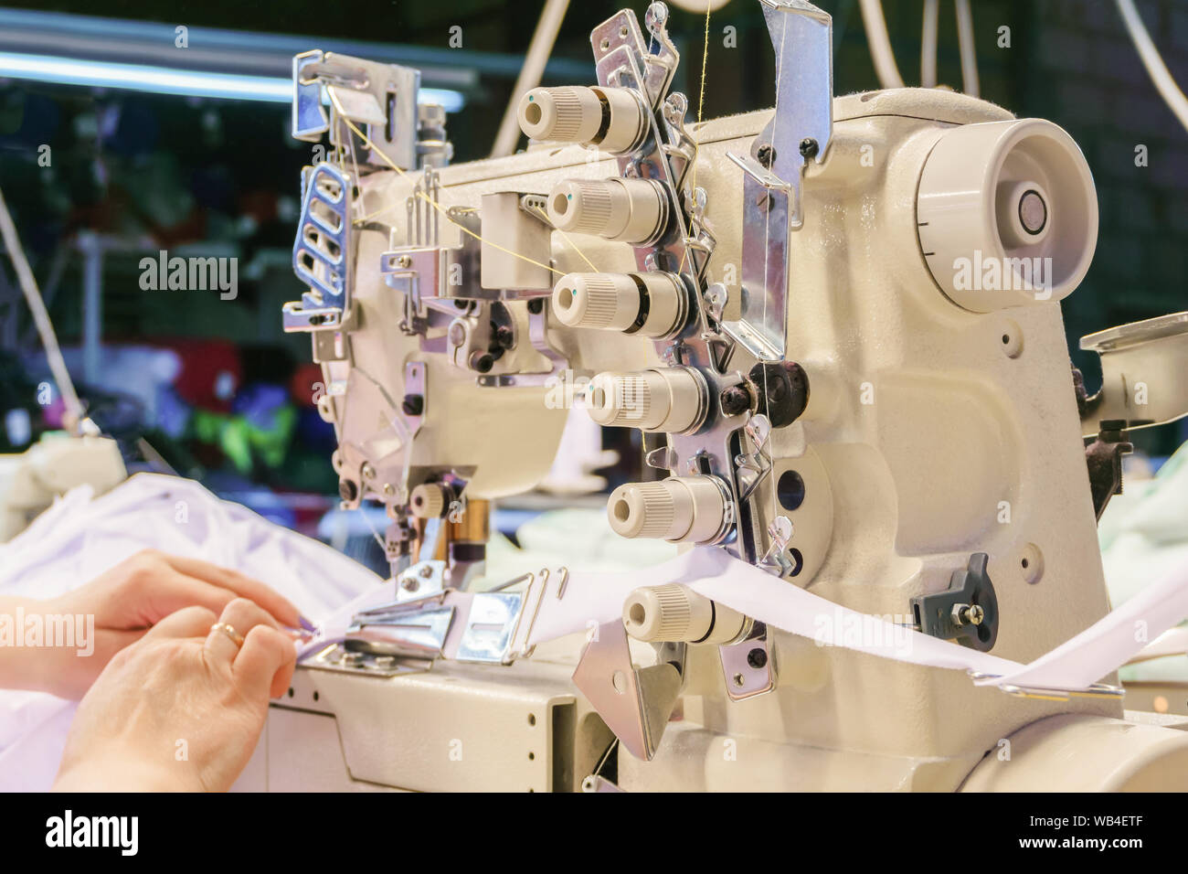 industrial overlock sewing machine and hands of seamstress at work in