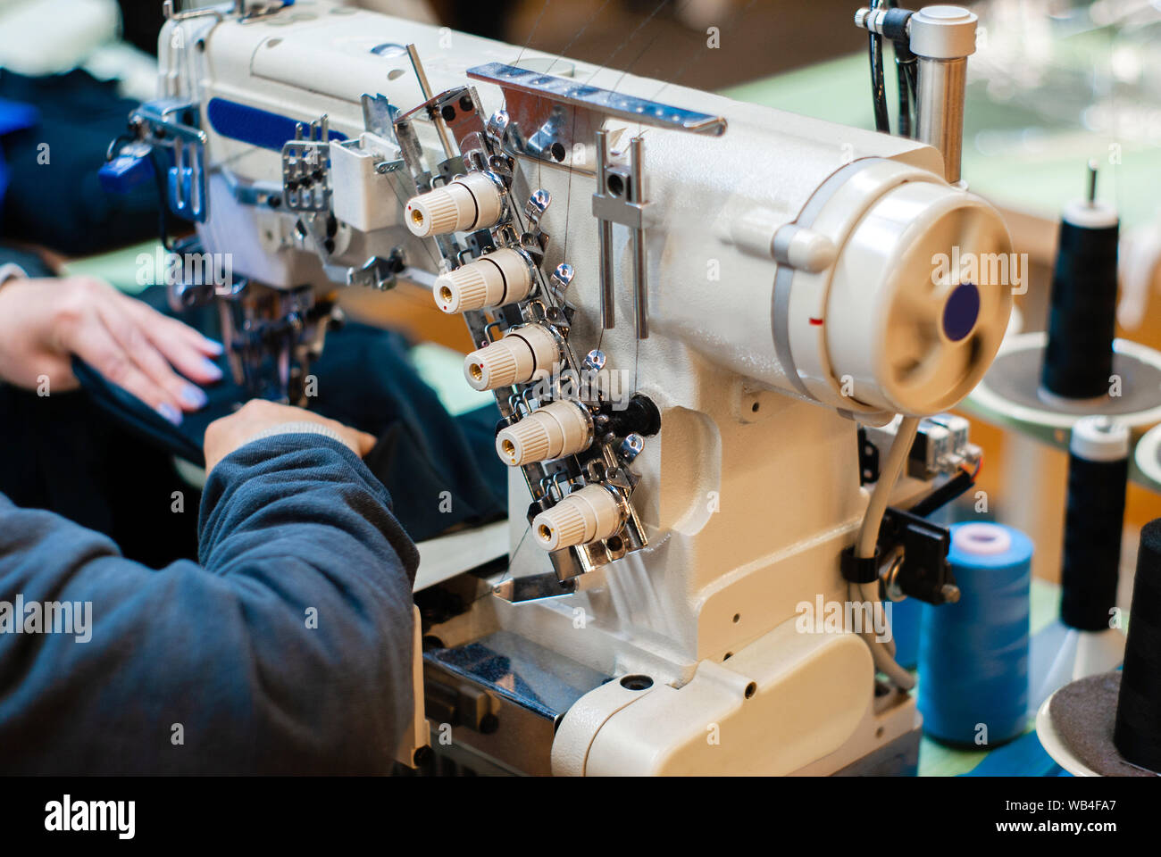 industrial overlock sewing machine and hands of seamstress at work in