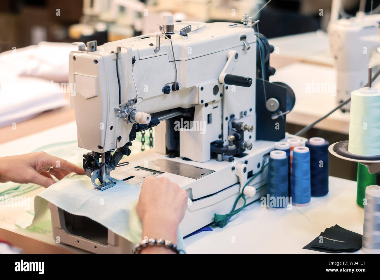 industrial overlock sewing machine and hands of seamstress at work in