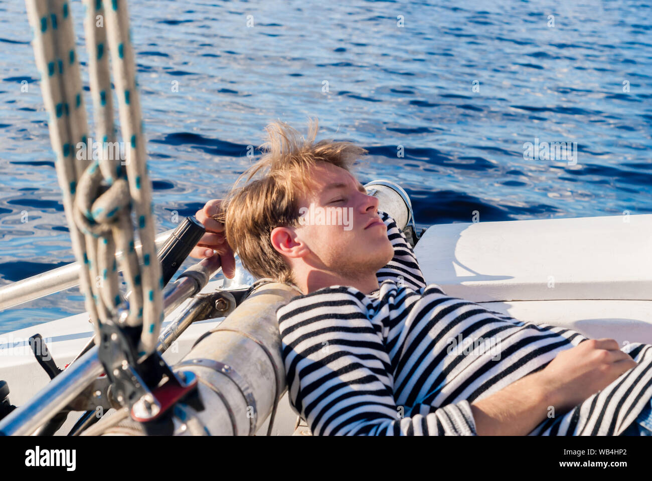 young male yachtsman napping aft of the yacht on a sunny day during forced inactivity during calm weather Stock Photo