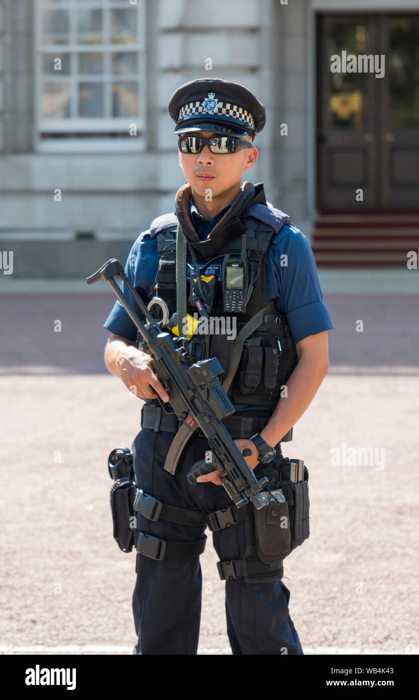 Male armed Metropolitan Police officer carrying a gun outside Buckingham Palace in City of Westminster, Central London, England, UK. Stock Photo