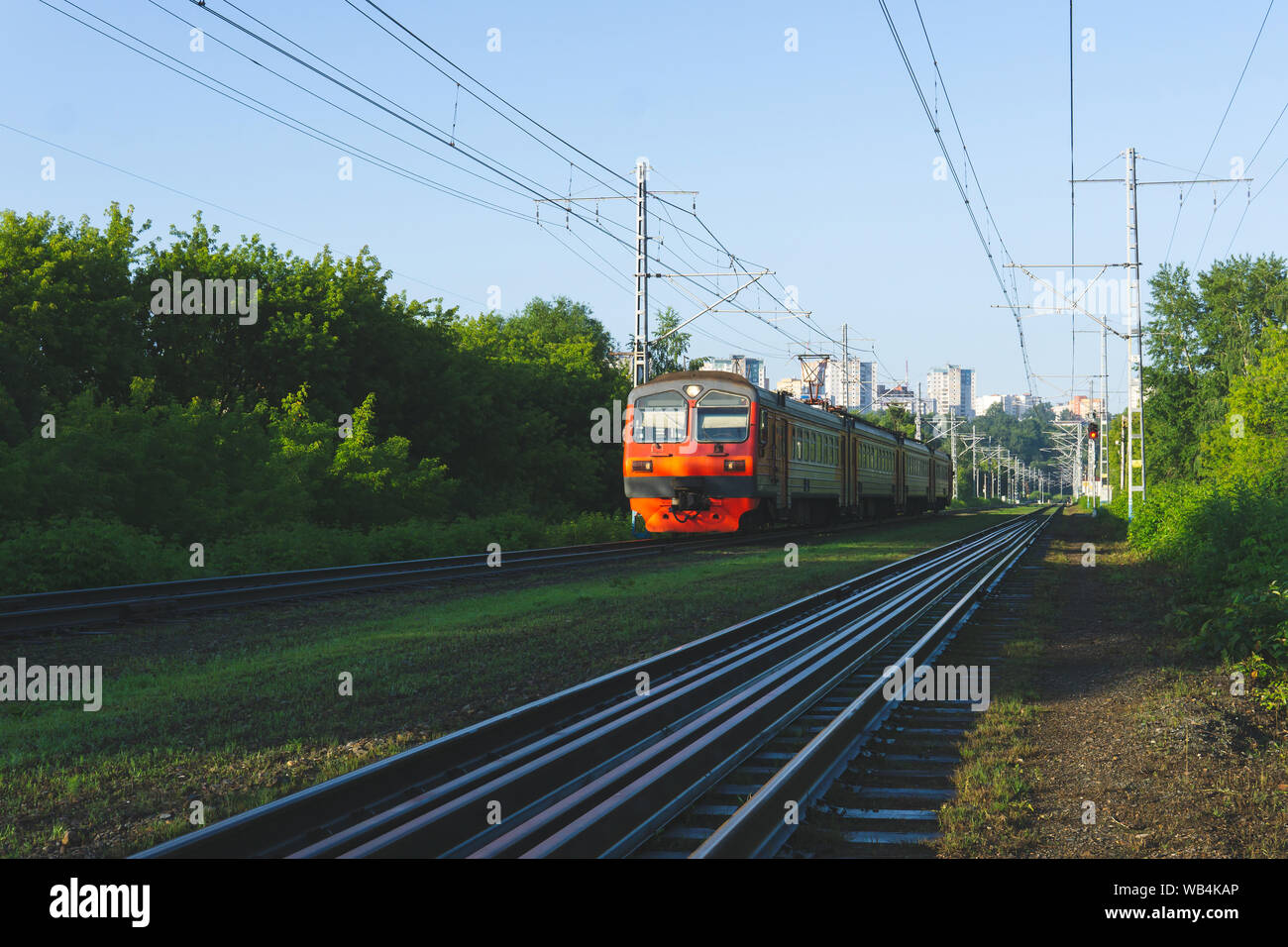 morning suburban landscape with electric commuter train moving from the city on the horizon Stock Photo