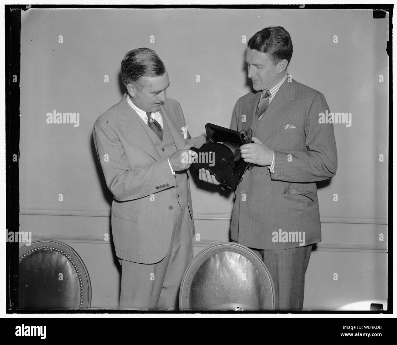 Edison receives first anti-glare lamp. Washington, D.C., May 17. Charles Edison, Asst. Sec. of the Navy and son of the late Thomas A. Edison, left; was presented with the first Polaroid lighting unit, a lamp free from glaring reflection. The lamp, praised by scientists as heralding a great advance in artificial illumination, employs the regulation incandescent light source as perfeted by Thomas A. Edison but passes the light through a sheet of the new light controlling material, Polaroid, to remove the light waves responsible for refelcted glare, one of the worst visual hazards of illumination Stock Photo