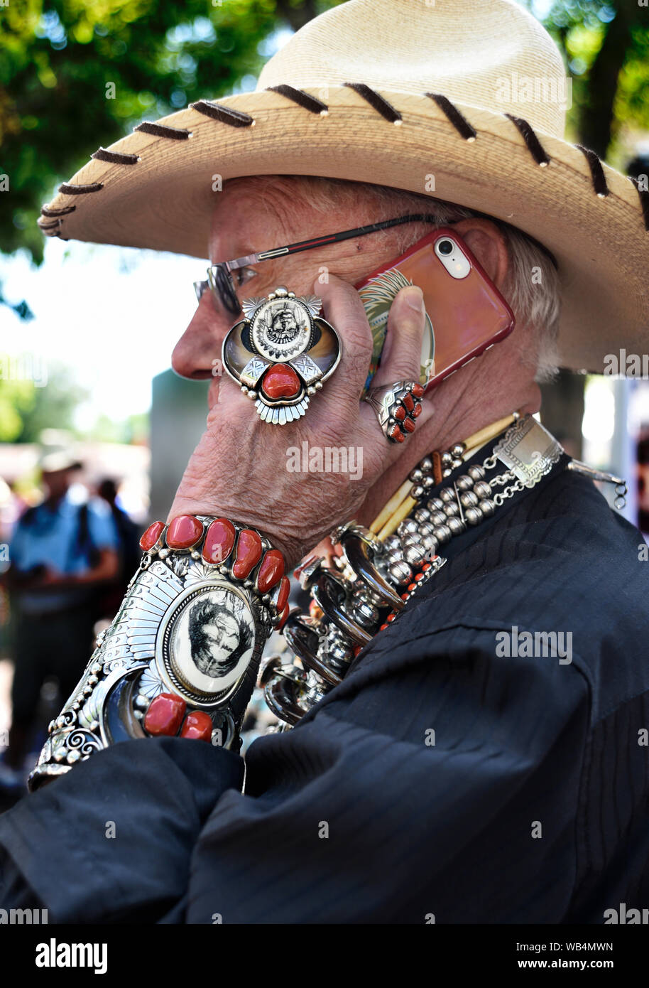 A tourist wearing Native American jewelry uses his smart phone at the annual Santa Fe Indian Market in New Mexico, USA Stock Photo