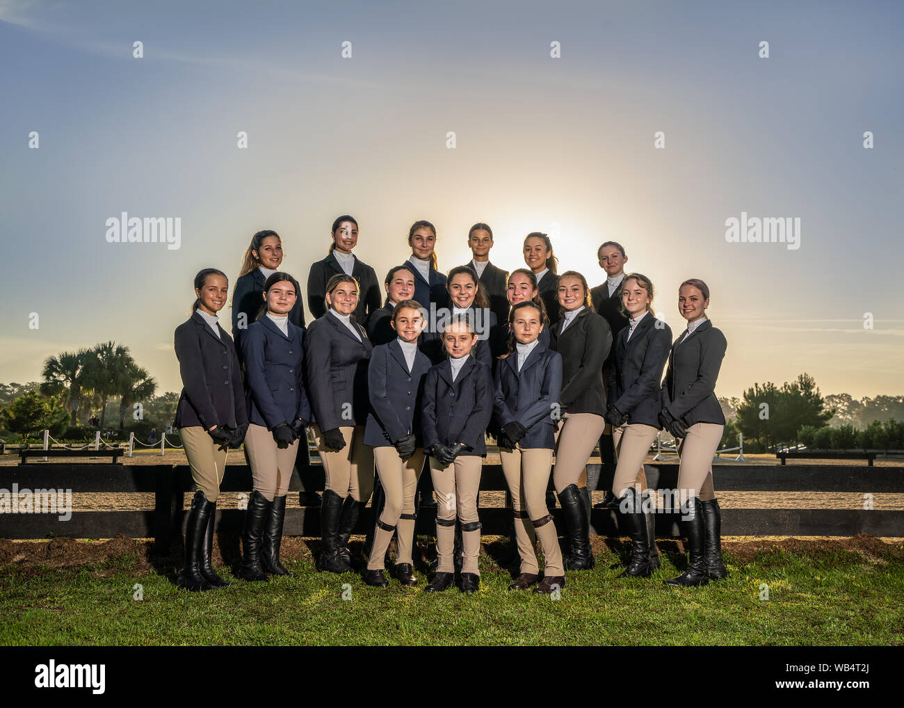 A group of young female english riders in uniform are posing for the camera together outside before their equestrian competition Stock Photo