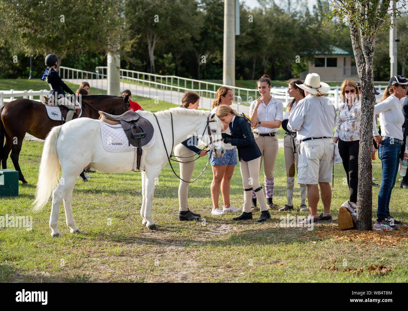 A group of riders, parents and coaches at a horse show standing together and talking.  Natural shot Stock Photo