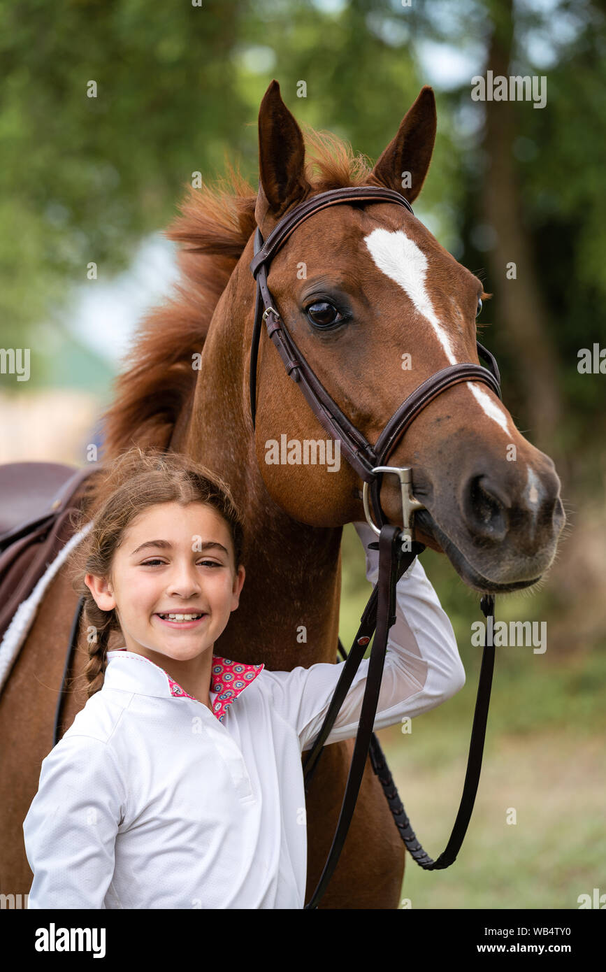 Portrait of a young girl holding her horse and smiling at the camera