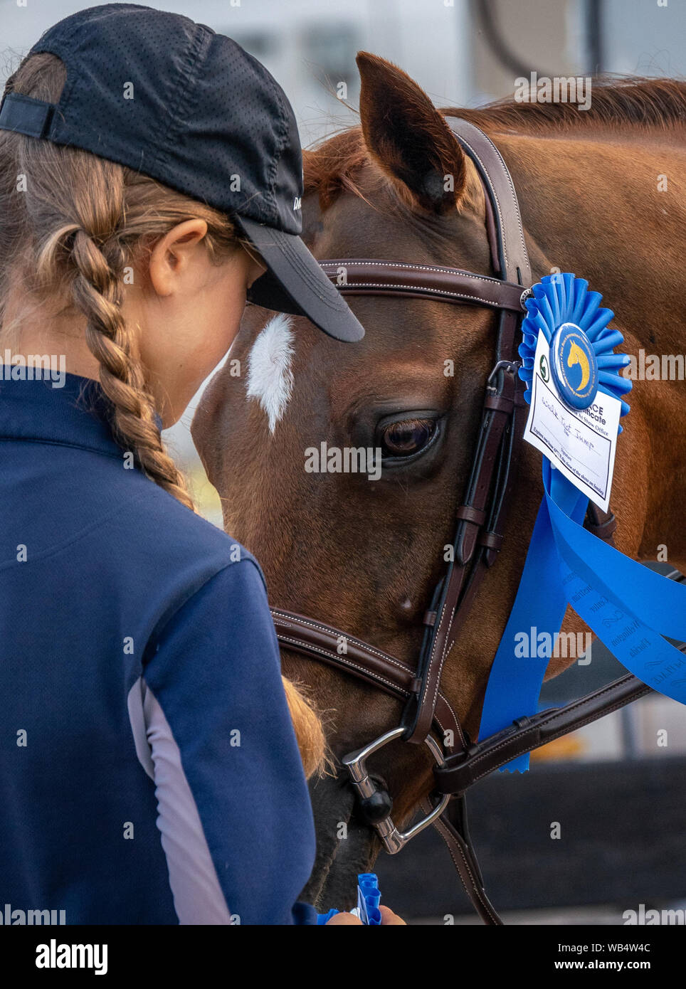 A young rider is talking to her champion horse after the horse show Stock Photo