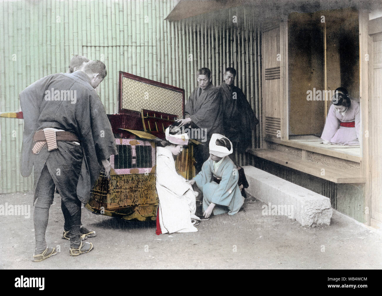 [ 1900s Japan - Japanese Bride Arriving at New Home ] —   Japanese Marriage: The bride arrives at the groom's house in a kago (palanquin) during an arranged marriage (omiai). This image comes from 'The Ceremonies of a Japanese Marriage,' published in 1905 (Meiji 38) by Kobe based photographer Teijiro Takagi.  Original text: 'The bride gets out of the 'Kago' and is received by the bridegroom's servants.'  20th century vintage collotype print. Stock Photo