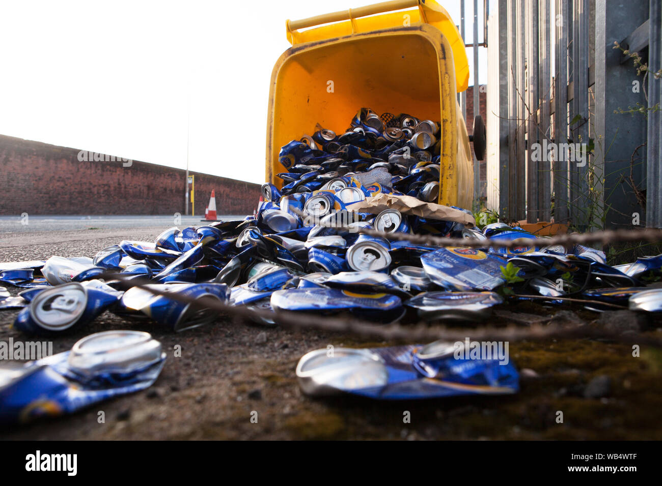 Yellow recycle box with hundreds of beer cans scattered on the street