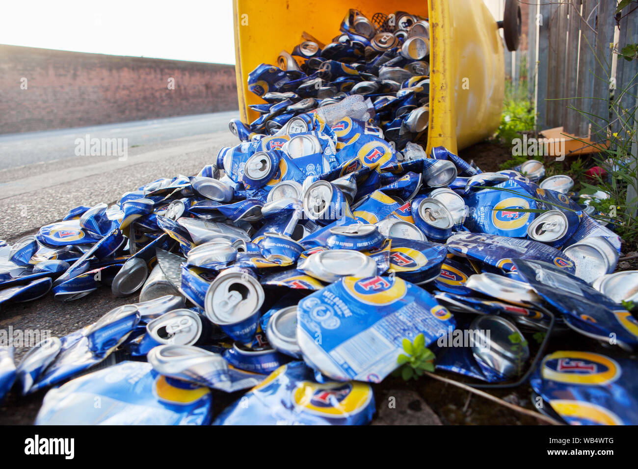 Yellow recycle box with hundreds of beer cans scattered on the street