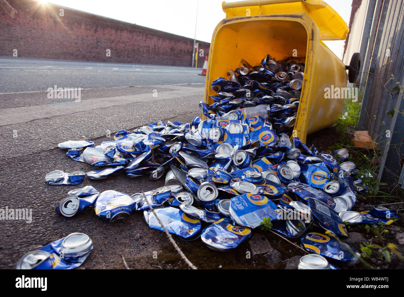 Yellow recycle box with hundreds of beer cans scattered on the street