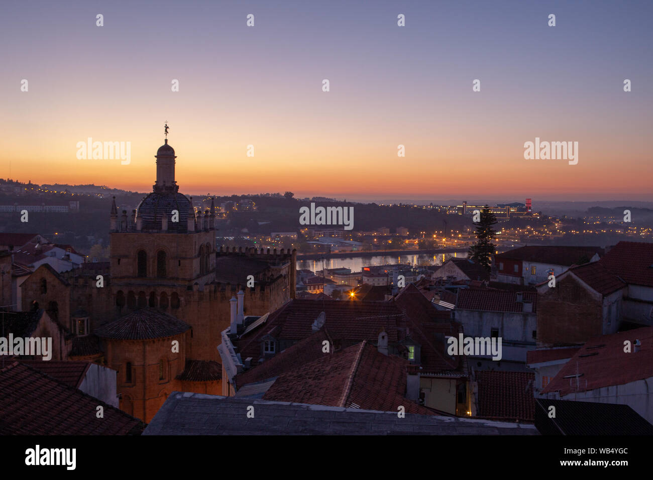 A panoramic view of the city of Coimbra with Sé Velha de Coimbra ( the Old Cathedral) overlooking the Rio Mondego in the sunset light -Portugal. Stock Photo