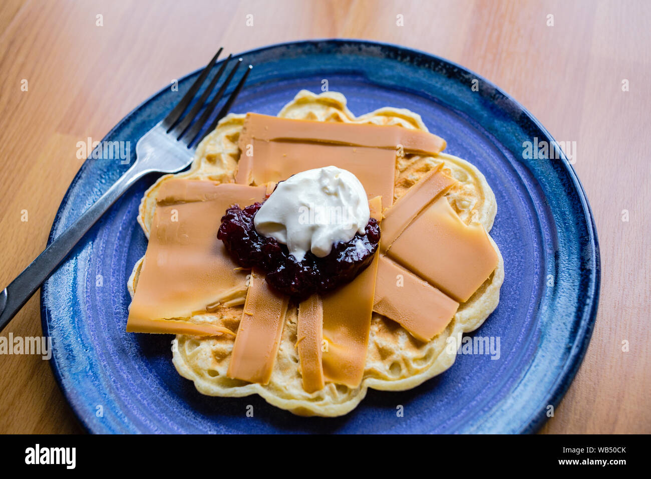 Norwegian brown cheese on a waffle with strawberry jam and sour cream Stock Photo