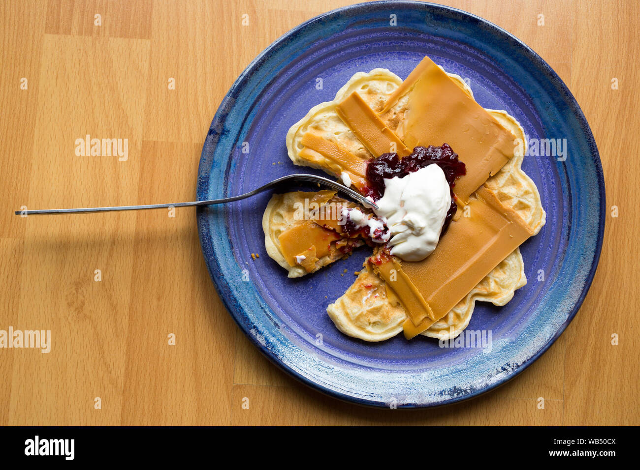 Norwegian brown cheese on a waffle with strawberry jam and sour cream