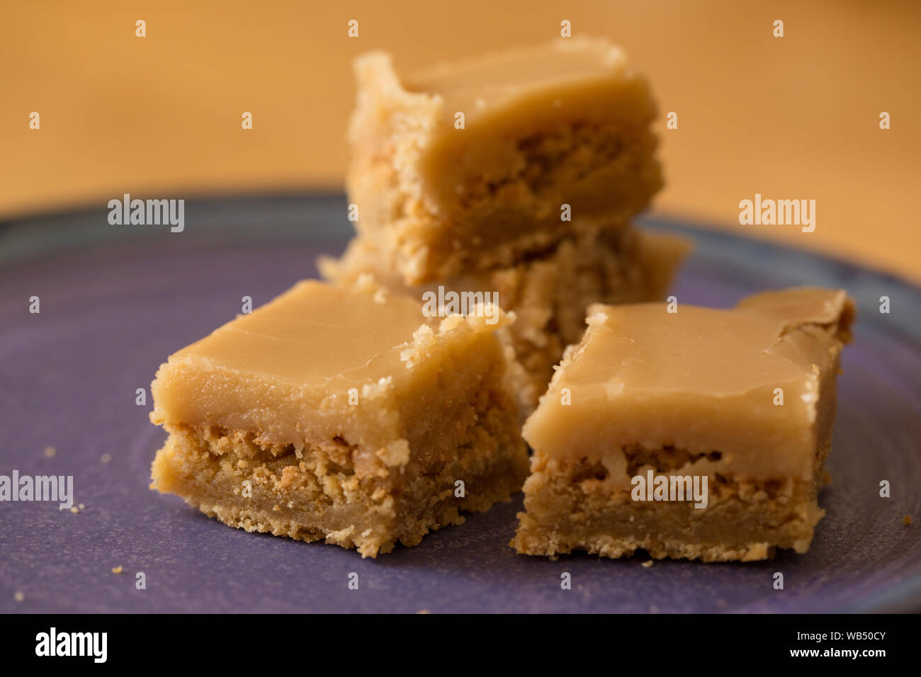 Four pieces of butterscotch square on blue plate with crumbs Stock Photo
