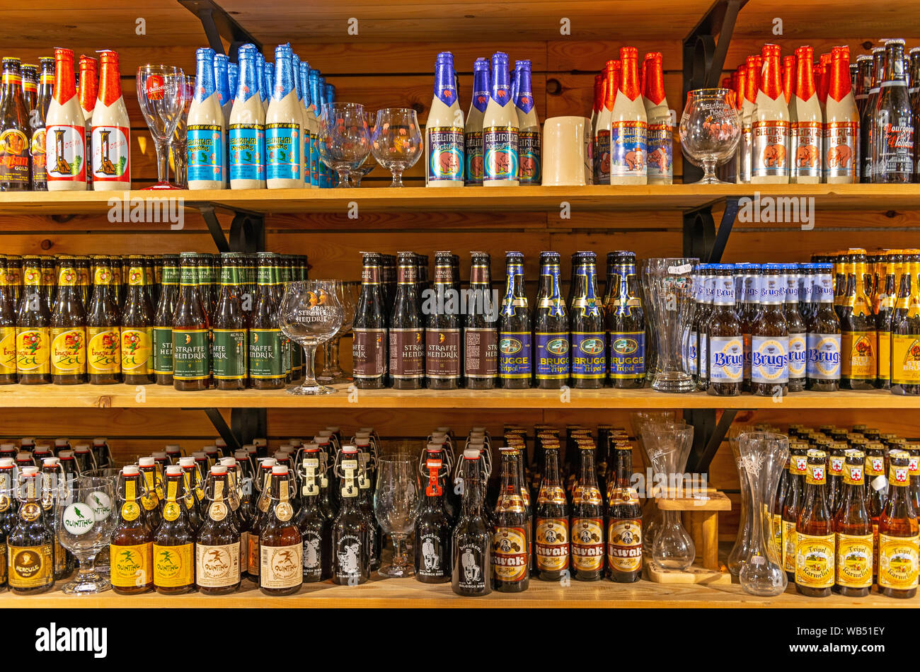 Store shelves with a collection of Belgian beer bottles and various brands with their specific glass in the city center of Bruges. Stock Photo