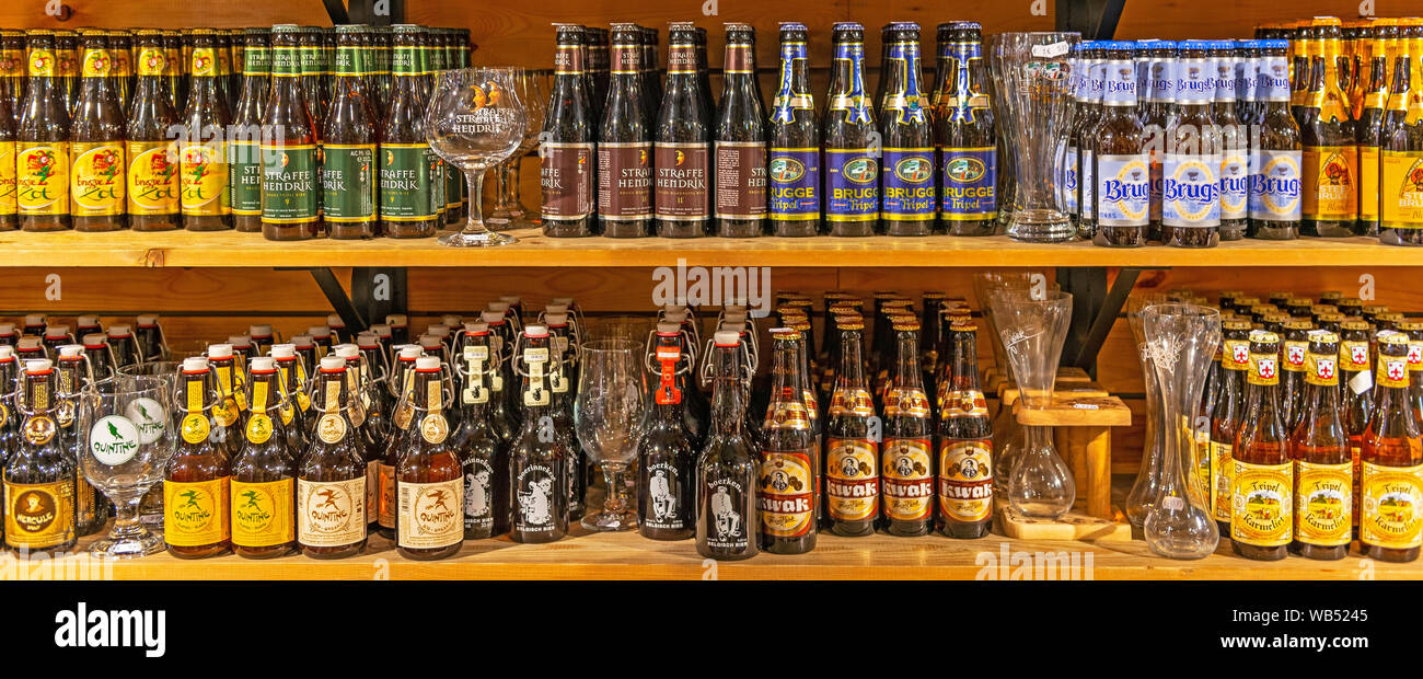 Belgian beers panorama with fitting drinking glasses on wooden shelves inside a tourist souvenir store in the city center of Bruges, Belgium. Stock Photo