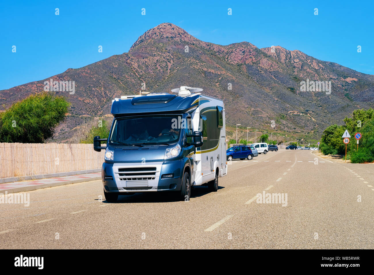 Rv cavaran on the road in Costa Smeralda on Sardinia Island in Italy in summer. Motorhome rving on motorway. Camper trailer on highway. Stock Photo