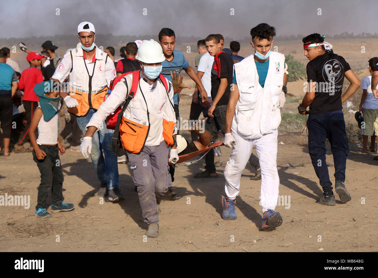 Khan Younis, Gaza Strip, Palestinian Territory. 23rd Aug, 2019. A wounded Palestinian protester is evacuated during clashes with Israeli troops following the tents protest where Palestinians demand the right to return to their homeland at the Israel-Gaza border. Credit: Mariam Dagga/APA Images/ZUMA Wire/Alamy Live News Stock Photo