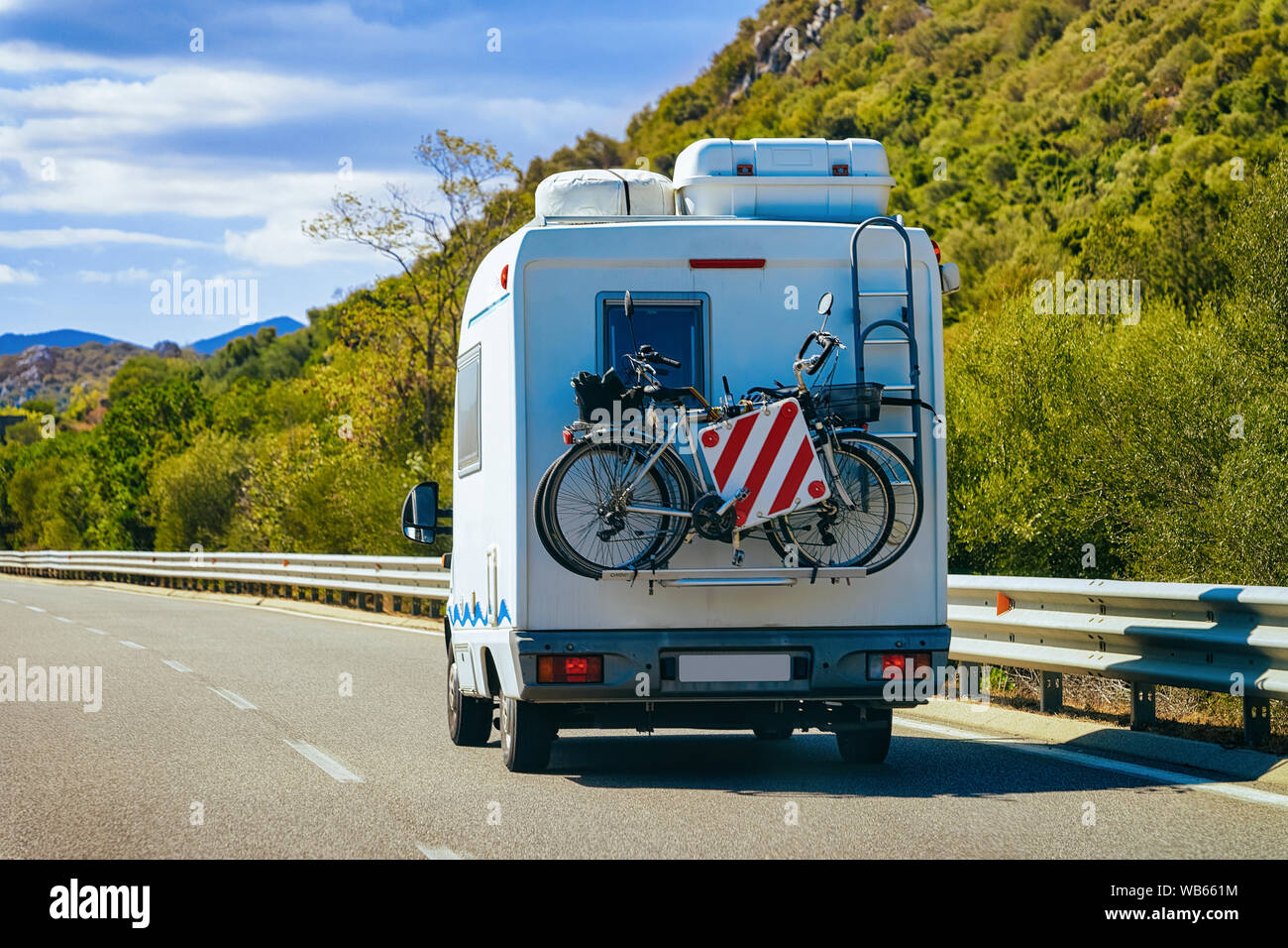 Rv cavaran with bicycles on the road in Costa Smeralda on Sardinia Island in Italy in summer. Motorhome rving and bikes on motorway. Camper trailer an Stock Photo
