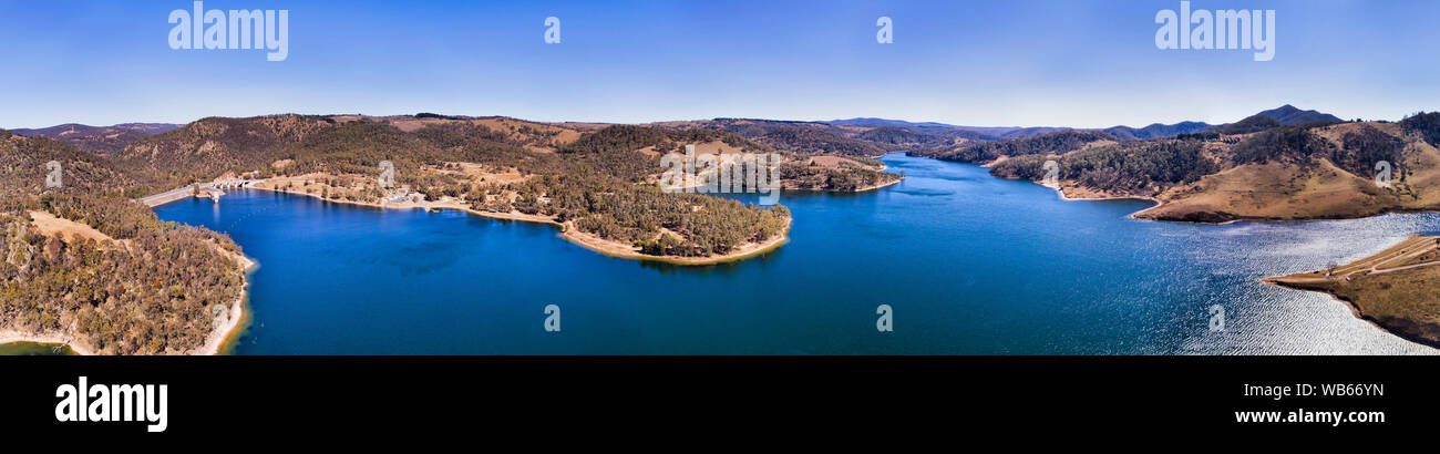 COxs river closed by a dam forming Lake Lyell between hill ranges in Blue Mountains of Australia on a sunny day in aerial wide panorama over water sur Stock Photo