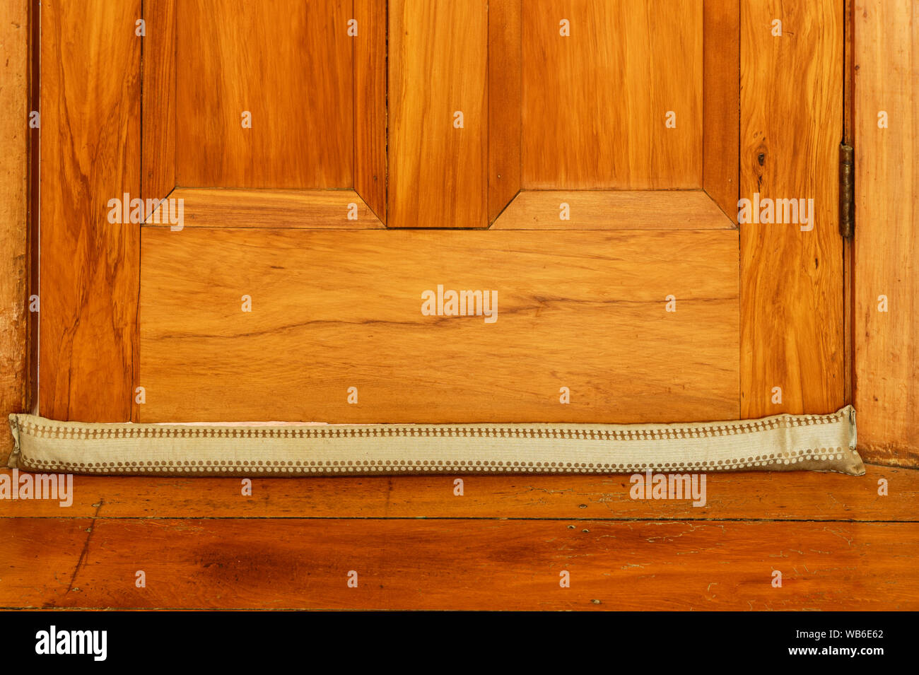 A material draught stopper used to prevent drafts in winter, on a wooden floor Stock Photo