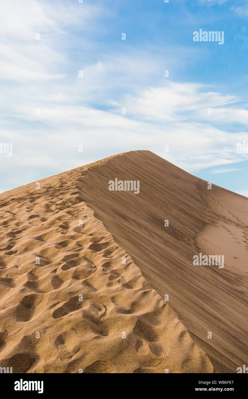 Vertical closeup shot of a beige sandy desert under a clear blue sky Stock Photo
