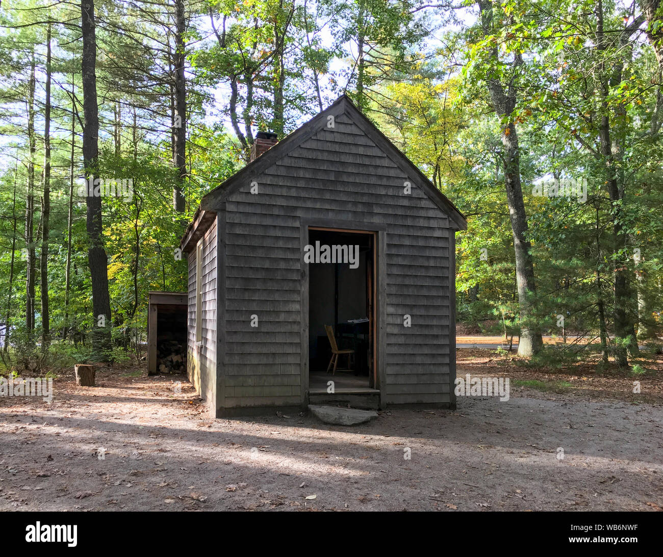 Replica of Henry David Thoreau’s little one-room cabin in the woods, with chimney and woodshed, at Walden Pond in the autumn. Concord, MA. Stock Photo
