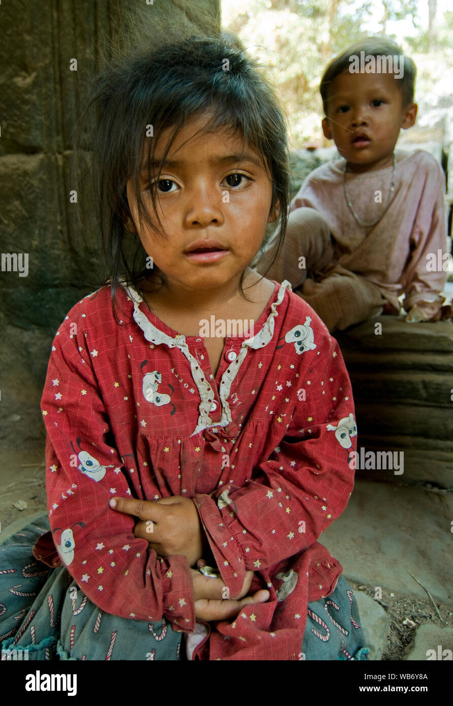 Two street children sitting in the ancient Khmer temple of Ta Prohm in the Angkor region near Siem Reap, Cambodia. Stock Photo