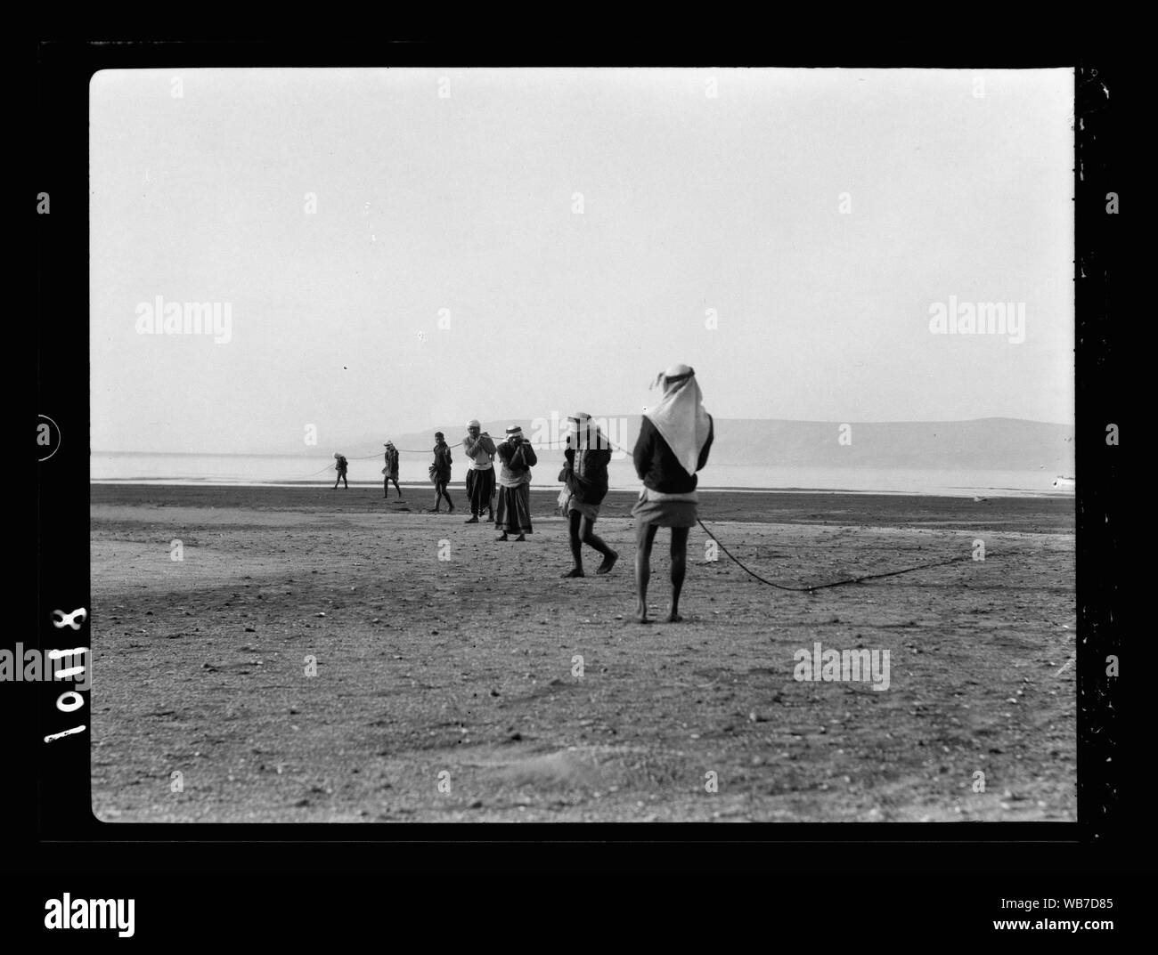 Fisherman drawing in large dragnet, spread out group, line of fishermen