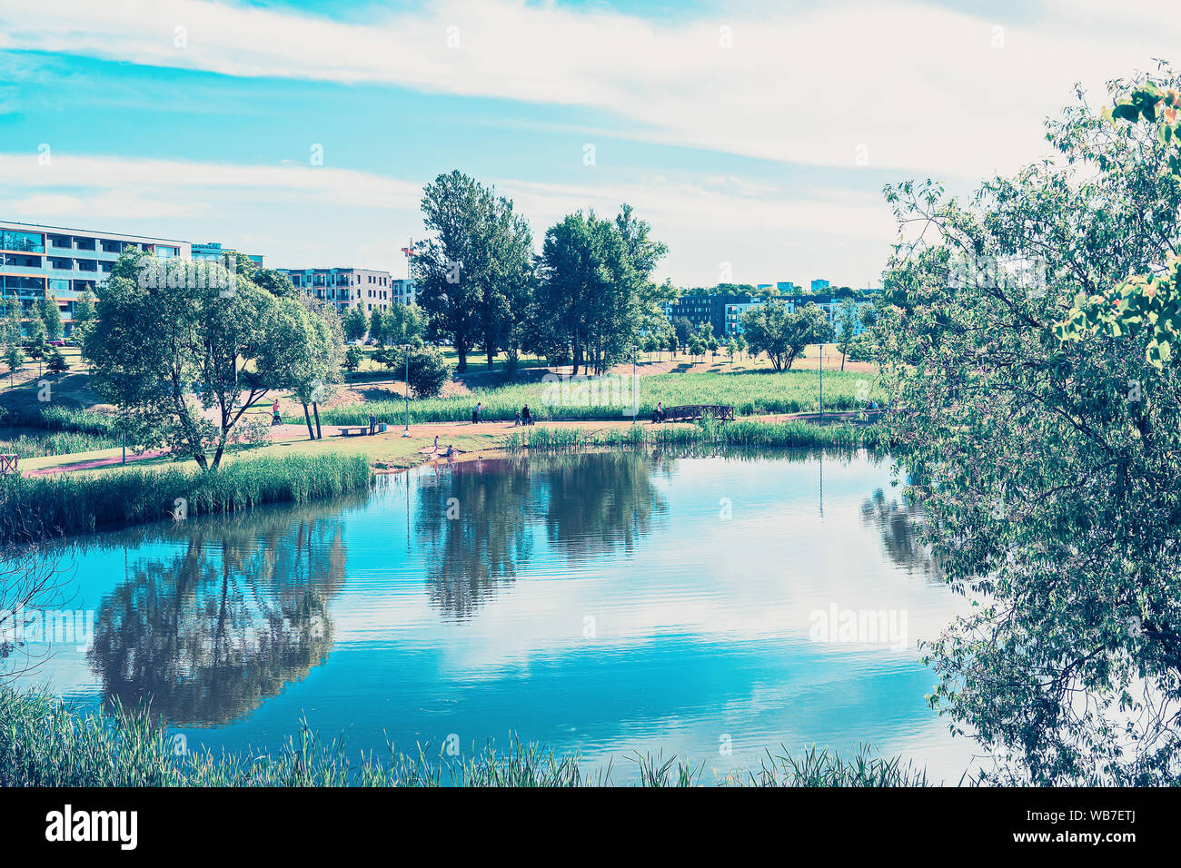 Landscape with park and pond and modern apartment buildings on the