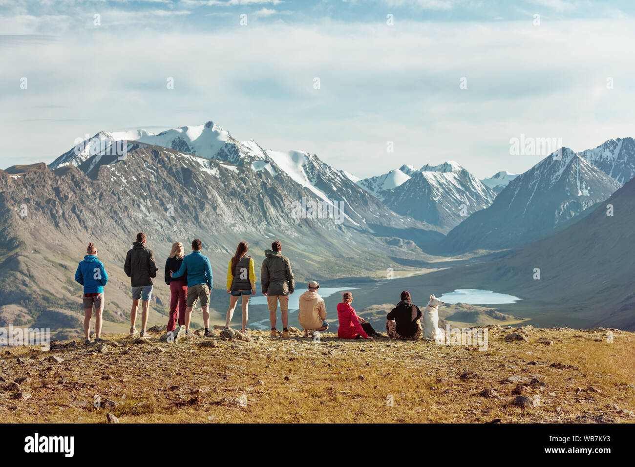Group of friends or tourists stands on view point in mountains area and having rest Stock Photo
