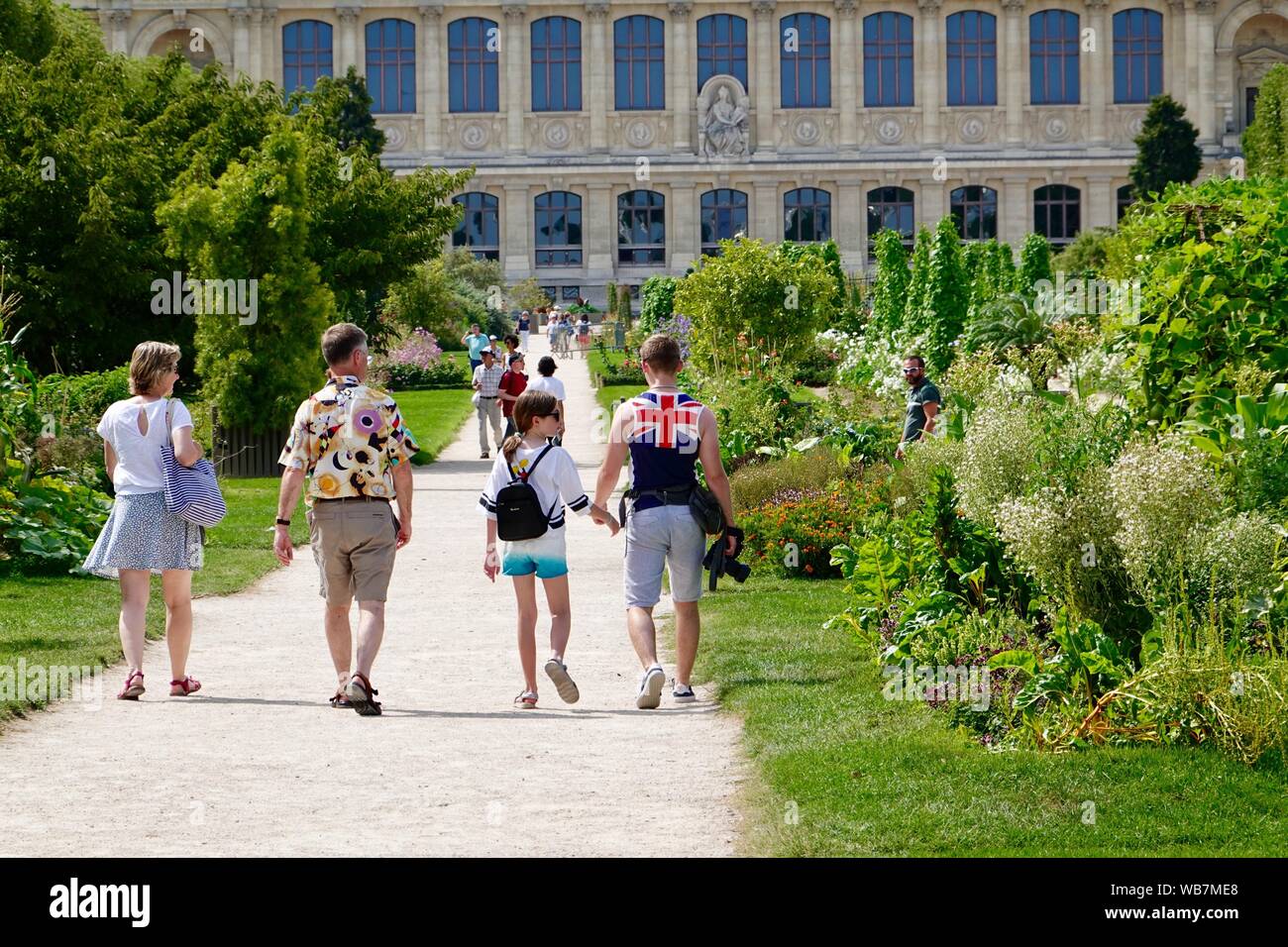 Family on vacation, walking towards the Muséum National d'Histoire Naturelle in the Jardin des Plantes, late summer, Paris, France Stock Photo