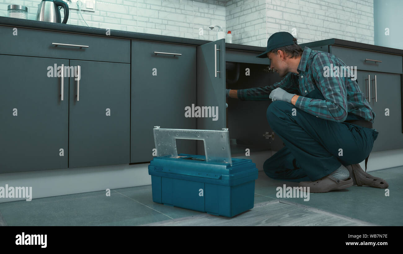 Portrait of mature handyman wearing uniform checking water pipes in the